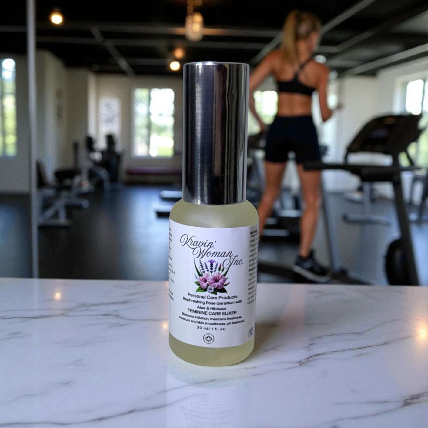 Luxury intimate personal care elixir by Kravin Woman Inc—rose, aloe, hibiscus, ACV, and honey formula; natural, handmade, woman-owned skincare from Calgary, Alberta. Bottle of Kravin Woman Elixirs product on a marble surface with a blurred gym background