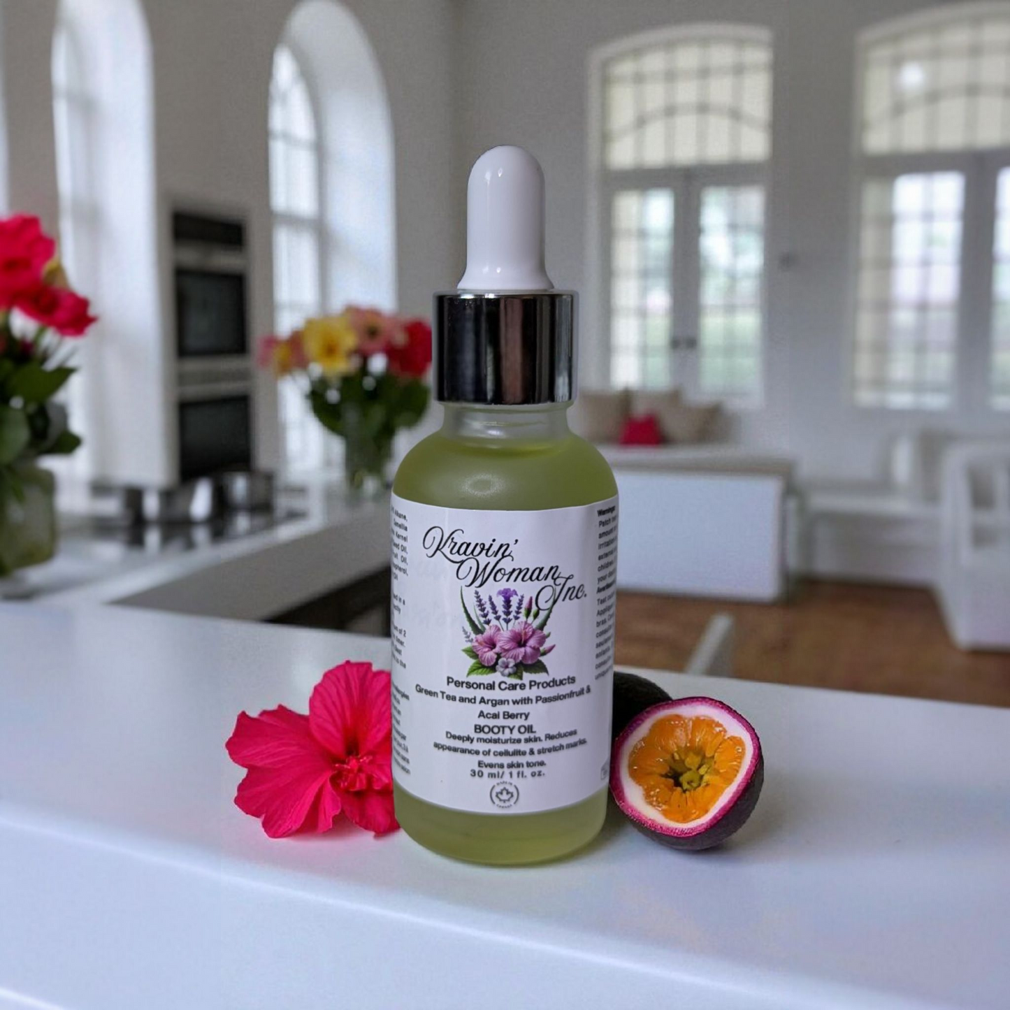 Kravin Woman Inc luxury booty oil—passionfruit, green tea, and argan for natural brightening and cellulite support; handmade, eco-friendly, female Black-owned skincare from Calgary, Alberta, Canada. Bottle of Kravin woman inc. product on a kitchen counter with flowers and a fruit.