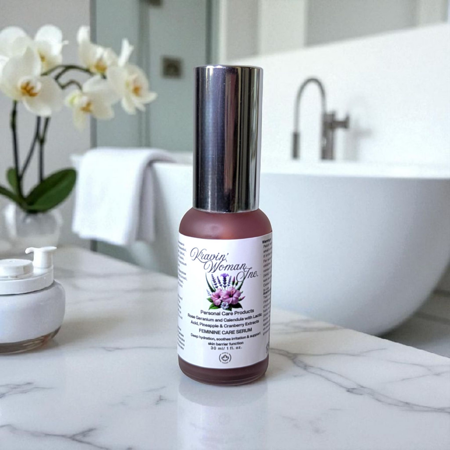 Handmade feminine care serum by Kravin Woman Inc—pineapple and cranberry infused natural intimate care in a luxury frosted bottle; eco-friendly and female-owned in Calgary, Canada. Serum bottle on a bathroom counter with a blurred background